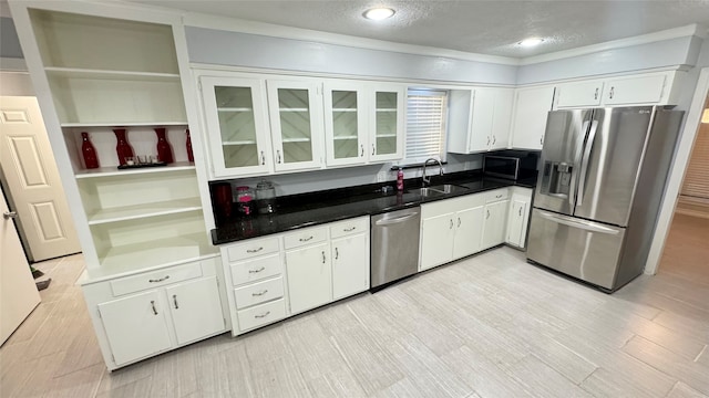 kitchen featuring sink, light wood-type flooring, a textured ceiling, white cabinetry, and stainless steel appliances