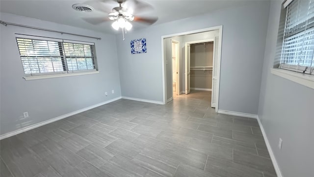 unfurnished bedroom featuring a closet, a spacious closet, and ceiling fan