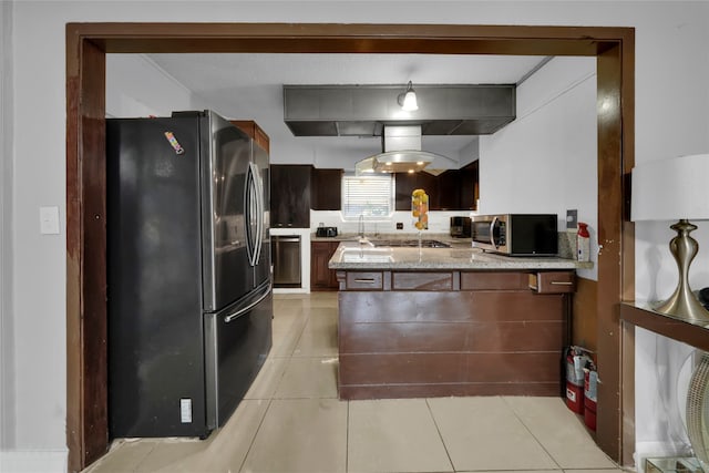 kitchen with hanging light fixtures, kitchen peninsula, stainless steel appliances, light stone countertops, and light tile patterned floors