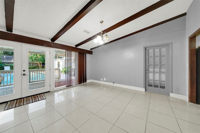 tiled empty room featuring french doors, a notable chandelier, lofted ceiling with beams, and a textured ceiling