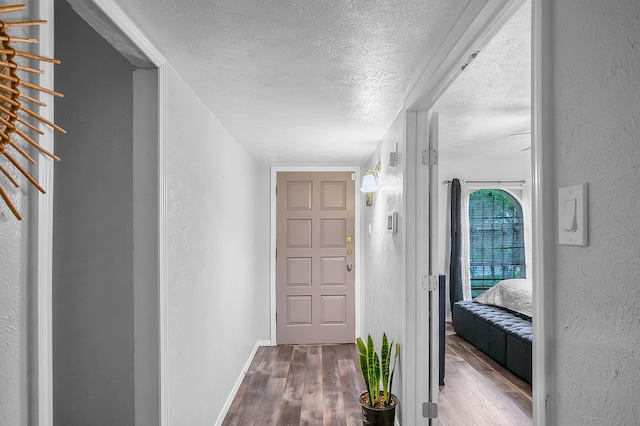 corridor featuring a textured ceiling and wood-type flooring