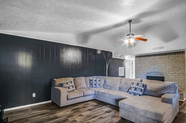 living room featuring a brick fireplace, wooden walls, dark wood-type flooring, and vaulted ceiling