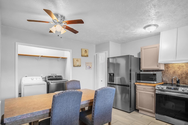 kitchen with light wood-type flooring, a textured ceiling, washing machine and clothes dryer, ceiling fan, and stainless steel appliances