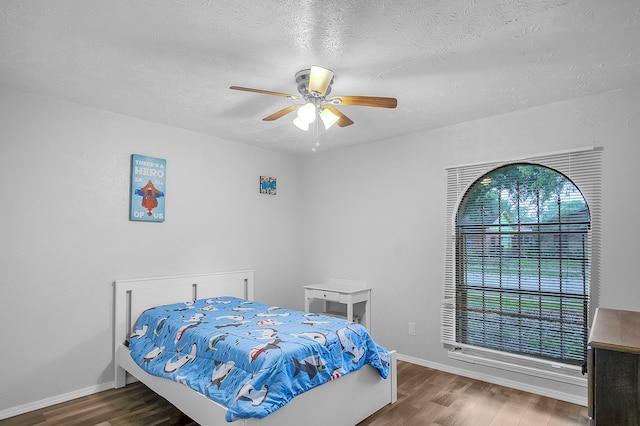 bedroom with ceiling fan, a textured ceiling, and dark hardwood / wood-style flooring