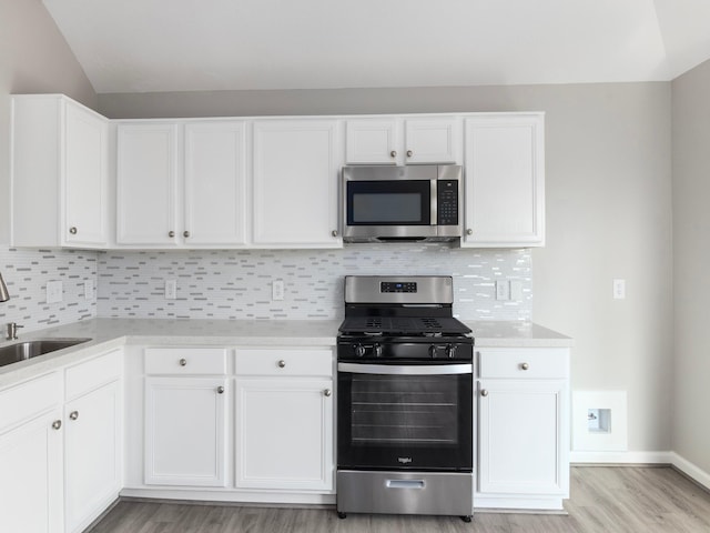 kitchen featuring light wood-type flooring, white cabinetry, appliances with stainless steel finishes, and tasteful backsplash