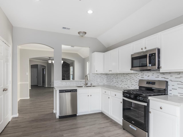 kitchen featuring white cabinetry, sink, stainless steel appliances, wood-type flooring, and vaulted ceiling