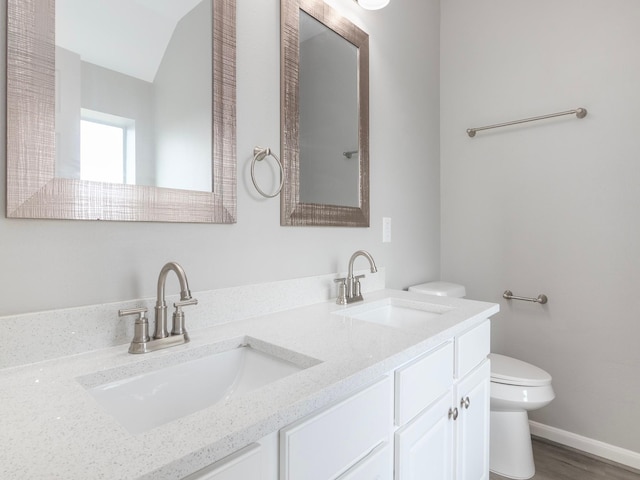 bathroom with vanity, toilet, wood-type flooring, and vaulted ceiling