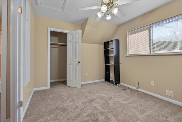 unfurnished bedroom featuring light carpet, a closet, vaulted ceiling, and ceiling fan