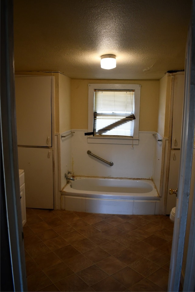 bathroom with vanity, toilet, a textured ceiling, and a washtub