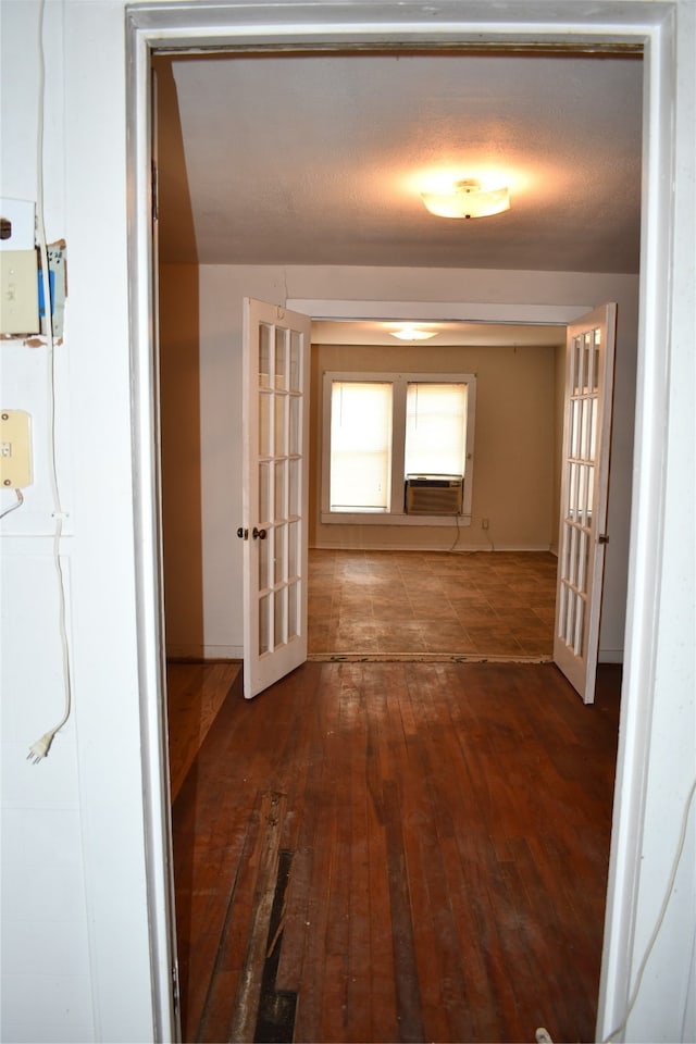 corridor with dark wood-type flooring, cooling unit, a textured ceiling, and french doors