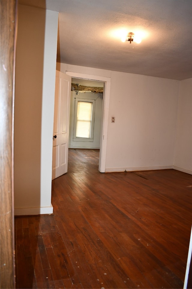 empty room with a textured ceiling and dark hardwood / wood-style flooring