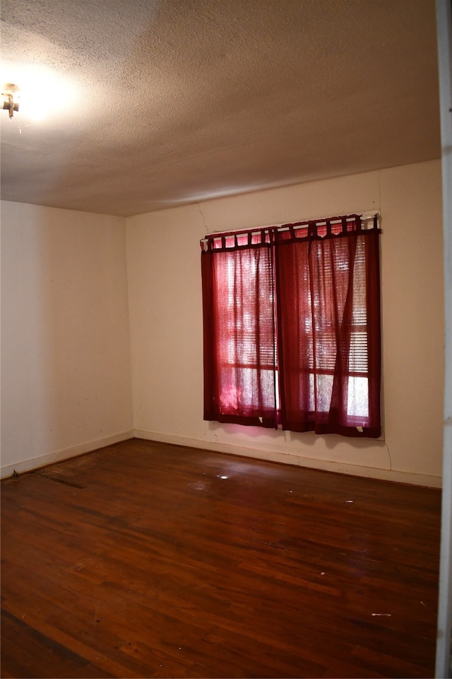 empty room featuring a textured ceiling and dark hardwood / wood-style flooring