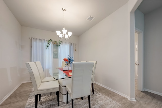 dining space featuring light hardwood / wood-style floors and an inviting chandelier