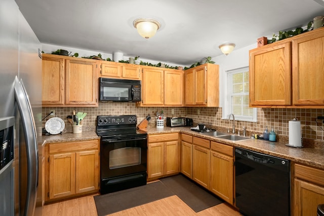 kitchen with sink, black appliances, light hardwood / wood-style floors, and tasteful backsplash