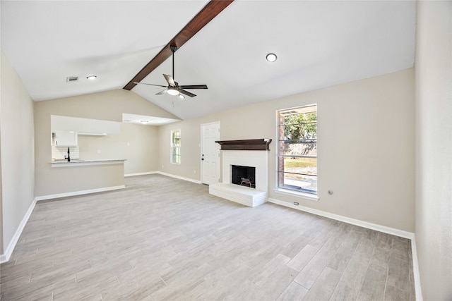 unfurnished living room featuring ceiling fan, lofted ceiling with beams, light wood-type flooring, and a fireplace