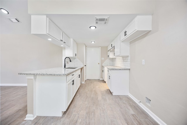 kitchen with light hardwood / wood-style flooring, white cabinetry, and sink