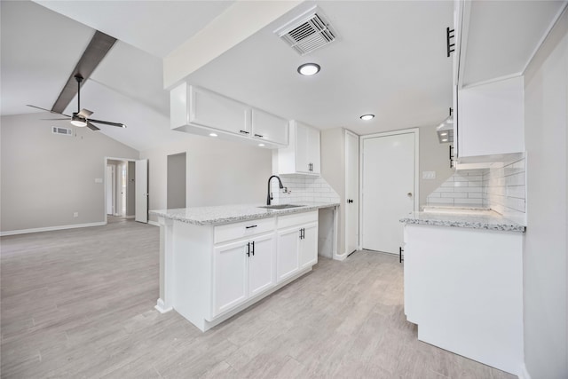 kitchen with decorative backsplash, light hardwood / wood-style flooring, white cabinetry, and sink