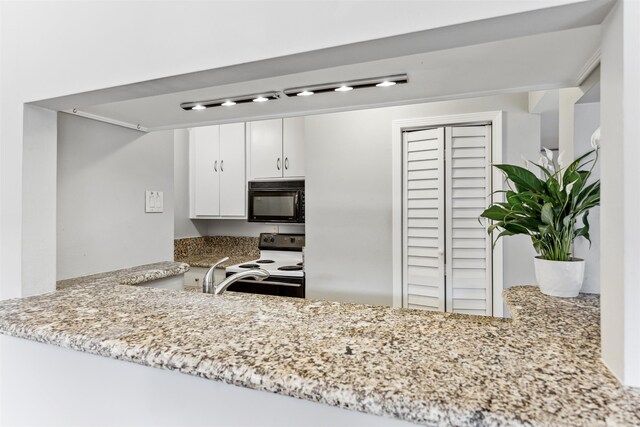 kitchen with electric stove, light stone countertops, kitchen peninsula, and white cabinets