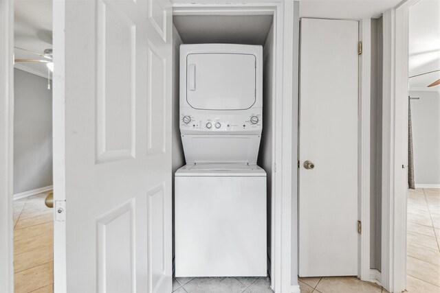 clothes washing area featuring stacked washer / dryer and light tile patterned flooring