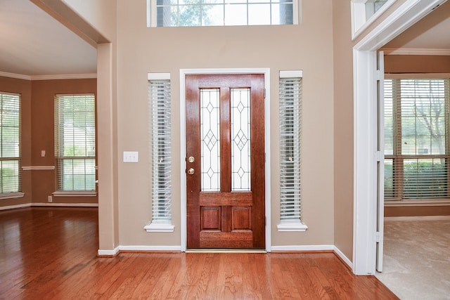 foyer entrance with light hardwood / wood-style floors and crown molding