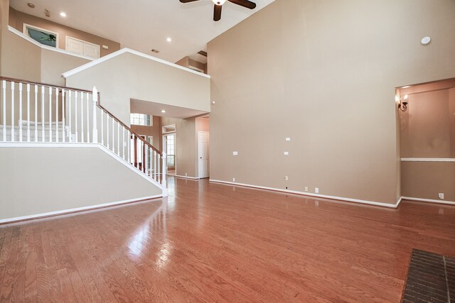 unfurnished living room with hardwood / wood-style floors, a high ceiling, and ceiling fan