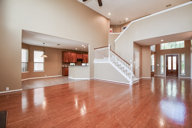 unfurnished living room with hardwood / wood-style flooring, a high ceiling, and ceiling fan