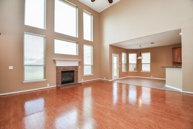 unfurnished living room featuring light hardwood / wood-style floors, a towering ceiling, and a wealth of natural light