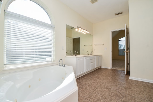 bathroom with vanity, a healthy amount of sunlight, a washtub, and tile patterned flooring