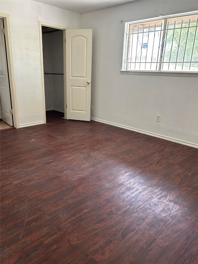 unfurnished bedroom with dark wood-type flooring and multiple windows