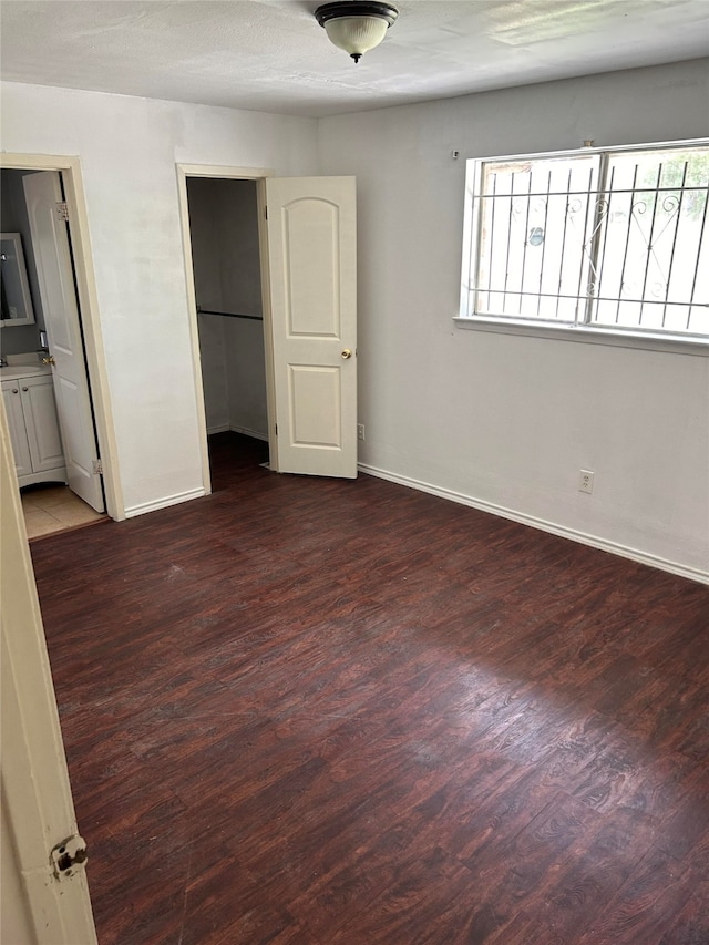 unfurnished bedroom featuring dark hardwood / wood-style floors and ensuite bath