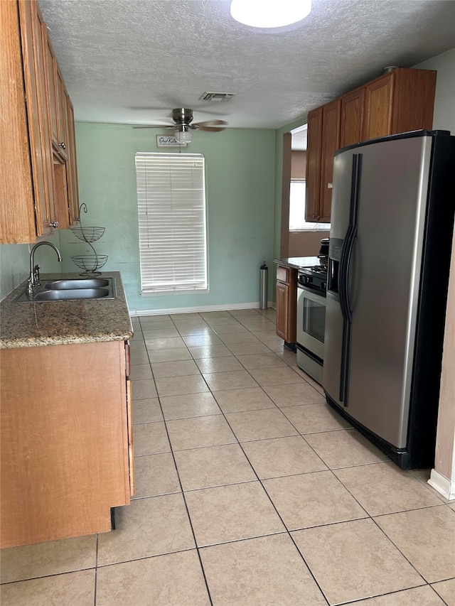 kitchen featuring light tile patterned floors, sink, stainless steel fridge with ice dispenser, range, and a textured ceiling