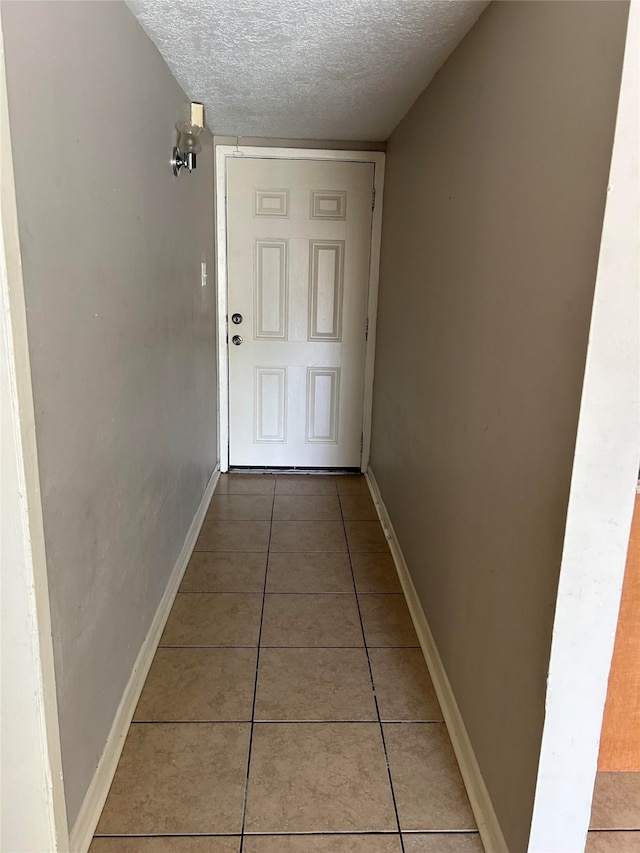 corridor featuring a textured ceiling and tile patterned flooring