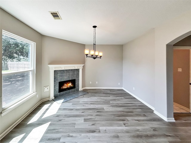 unfurnished living room featuring hardwood / wood-style floors, a tile fireplace, and plenty of natural light