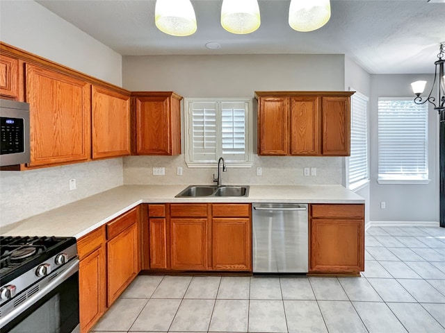 kitchen with appliances with stainless steel finishes, light tile patterned flooring, sink, hanging light fixtures, and an inviting chandelier