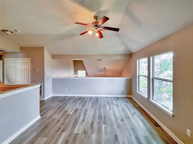 unfurnished living room with ceiling fan, vaulted ceiling, and light wood-type flooring