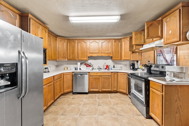 kitchen featuring a textured ceiling, appliances with stainless steel finishes, sink, and light tile patterned flooring