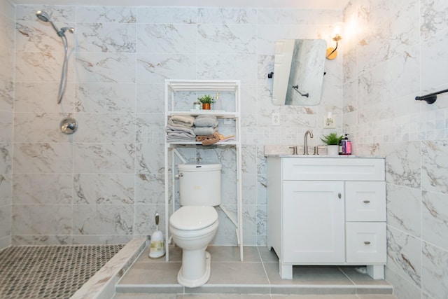 bathroom with tile patterned flooring, vanity, toilet, and tiled shower