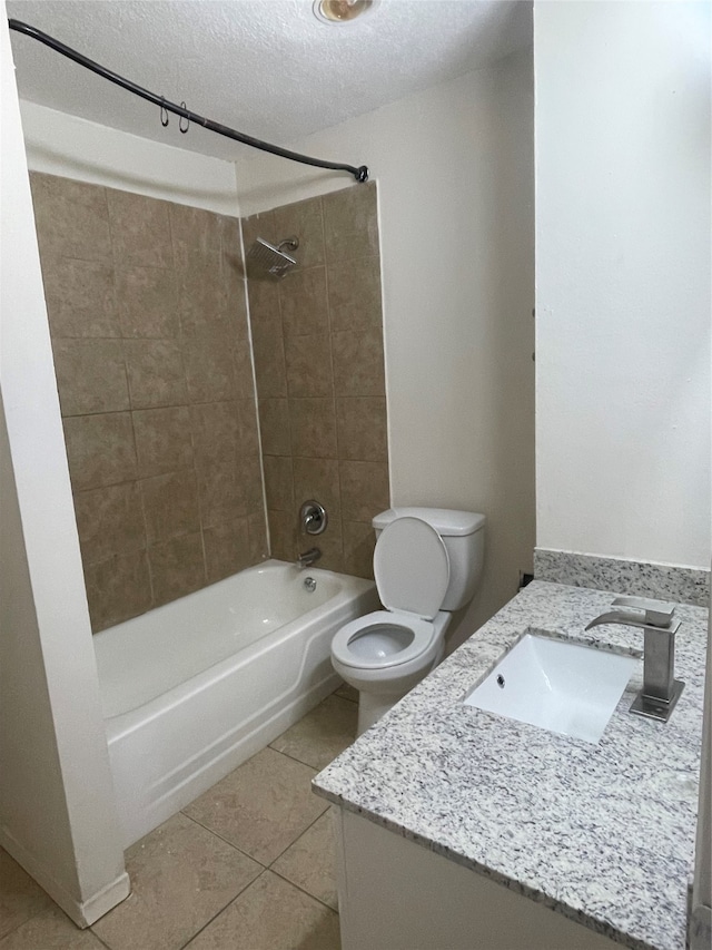 full bathroom featuring tiled shower / bath, a textured ceiling, toilet, vanity, and tile patterned floors