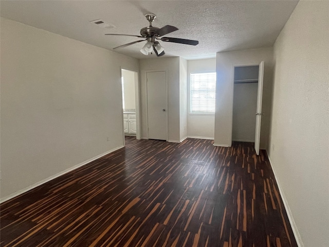 unfurnished bedroom with dark hardwood / wood-style flooring, a textured ceiling, and ceiling fan