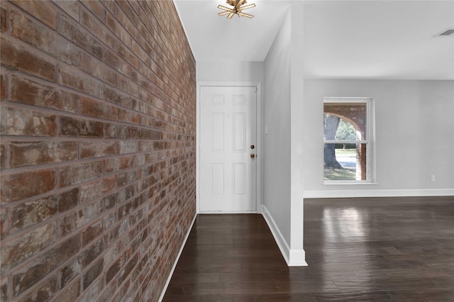 entrance foyer featuring dark hardwood / wood-style flooring and brick wall