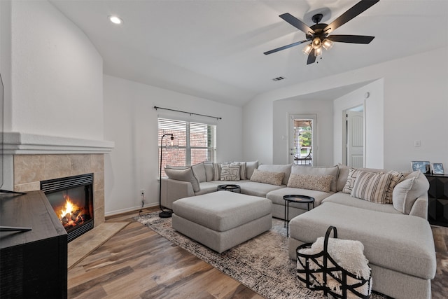 living room with vaulted ceiling, a fireplace, hardwood / wood-style flooring, and ceiling fan