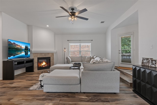 living room with lofted ceiling, dark wood-type flooring, a tile fireplace, and ceiling fan