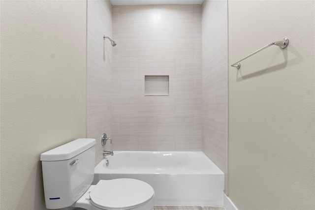 bathroom featuring tiled shower / bath combo and toilet