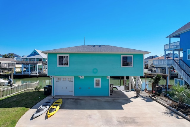 22819 Vida St, Galveston, TX 77554 - rear view of property with concrete driveway, a garage, a water view, and stairs