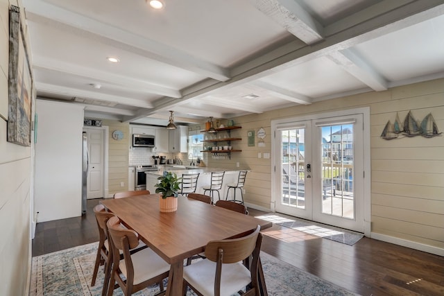 dining room featuring french doors, dark hardwood / wood-style floors, beam ceiling, and wooden walls