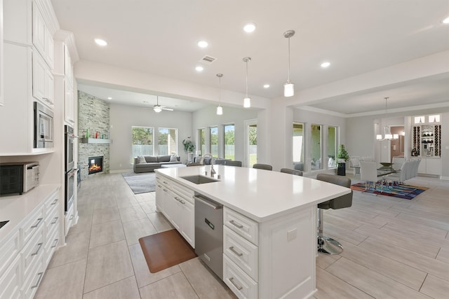 kitchen featuring sink, an island with sink, a kitchen breakfast bar, and white cabinets