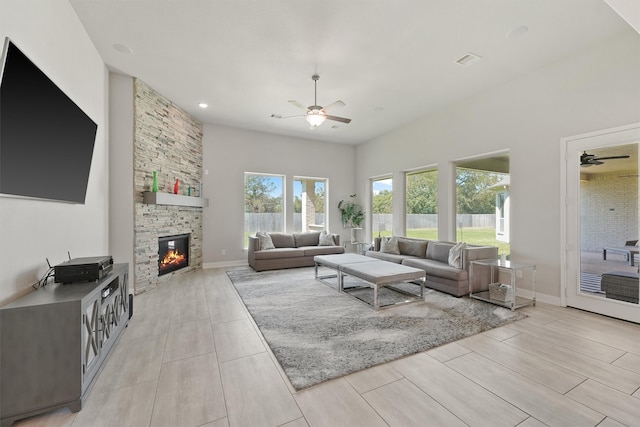 living room with ceiling fan and a stone fireplace