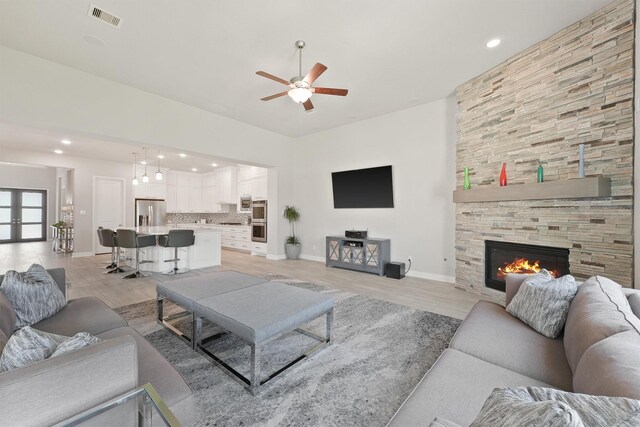 living room featuring ceiling fan, light wood-type flooring, and a fireplace