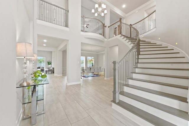 tiled entryway featuring a high ceiling, crown molding, and a chandelier