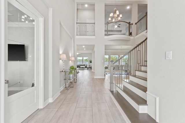 tiled foyer entrance with an inviting chandelier and a high ceiling